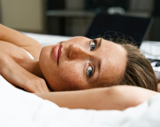 woman-lies-on-a-snow-white-bed-linen-next-to-synth-2023-11-27-05-02-26-utc 1